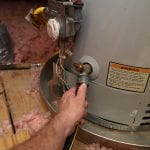 Hand attaches hose to a home water heater to perform maintenance