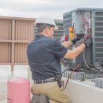 Technician checking for power on a rooftop condensing unit.