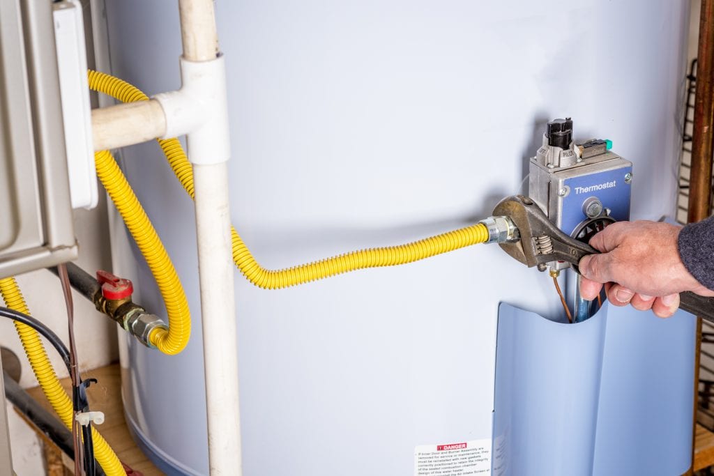 Handyman attaches a gasline to a water heater