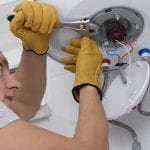 repairman with a wrench in his hand tightens the nuts on an electric boiler