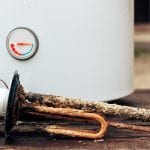heating element, rust and scale on boiler background, lying on wooden table.