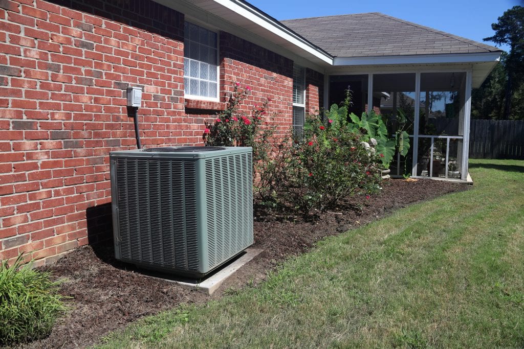 Air Conditioner system next to a home, modern clean with bushes and brick wall