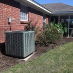 Air Conditioner system next to a home, modern clean with bushes and brick wall