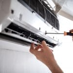 Electrician repairing air conditioner indoors