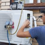 the worker installs the outdoor unit of the air conditioner on the wall of the house