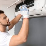 Male technician repairing air conditioner indoors