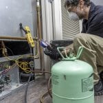 HVAC contractor wearing PPE, servicing a heat pump
